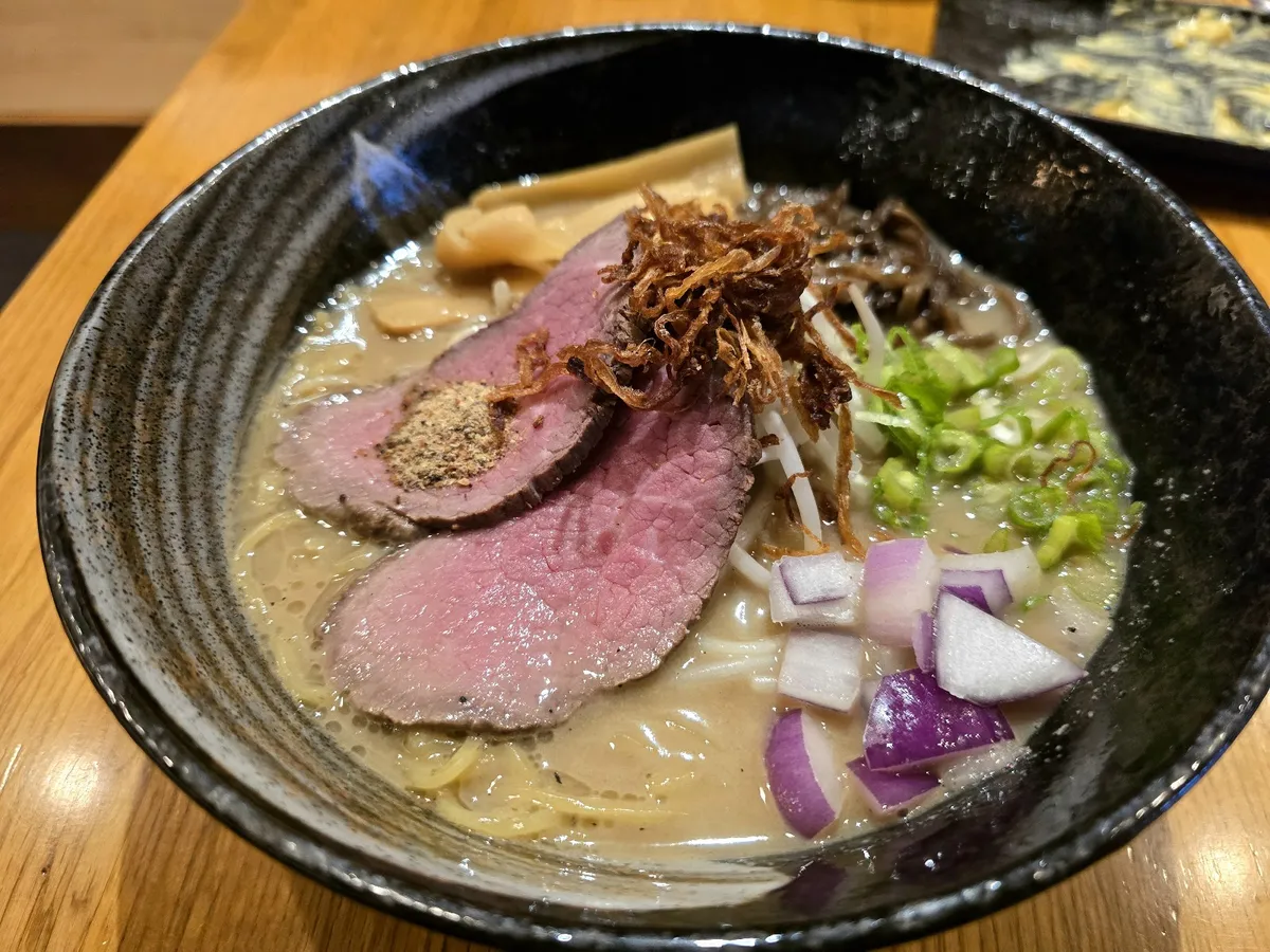 Ramen bowl with sliced beef, fried onions, and vegetables